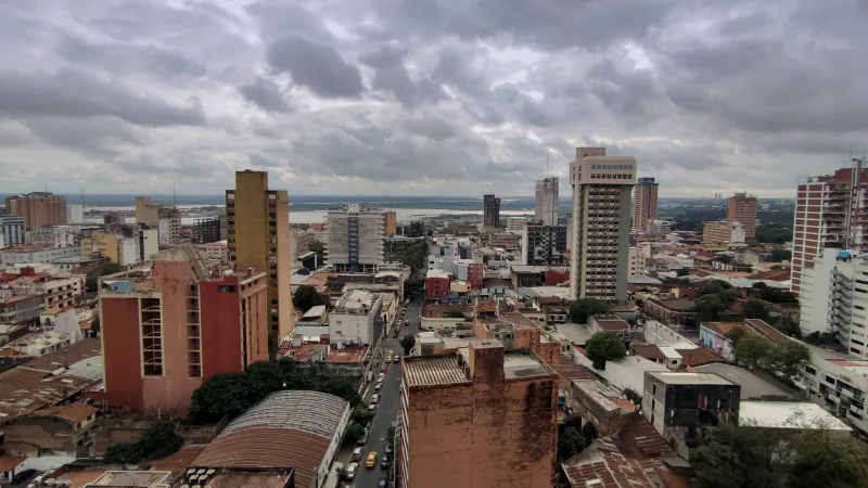 Asunción rooftops and taller buildings with a river in the distance