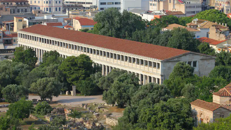 Reconstructed Stoa of Attalos: a long two-storey colonnaded building with a red-tiled roof above the excavated Agora.