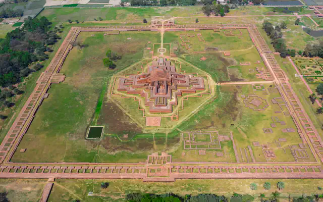 Aerial view of Somapura Mahavihara at Paharpur: a square enclosure of monastery cells around a cross-shaped central shrine, with low ruins across a grassy courtyard