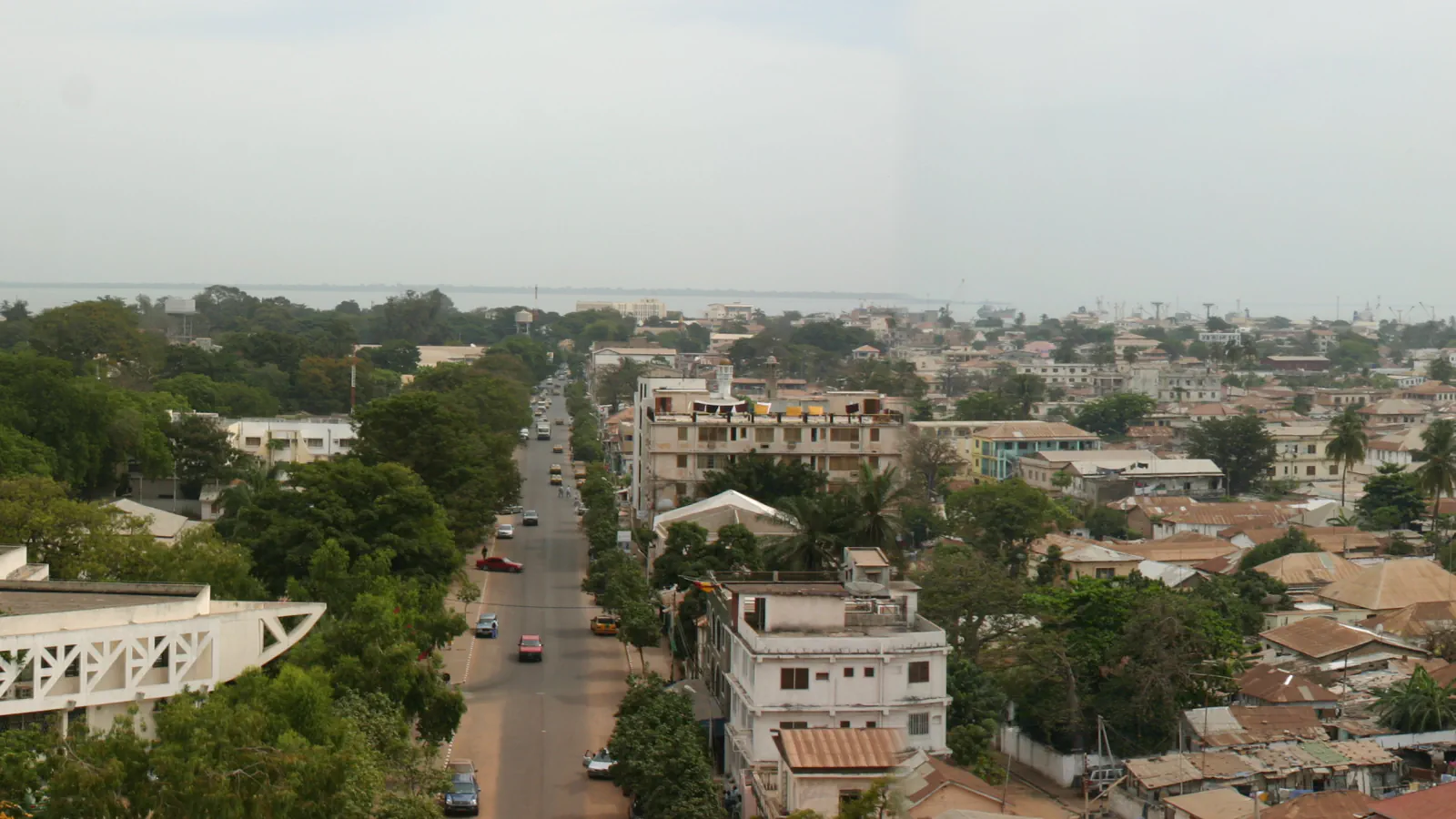 Strehe, drevesa in ulica proti obali v mestu Banjul