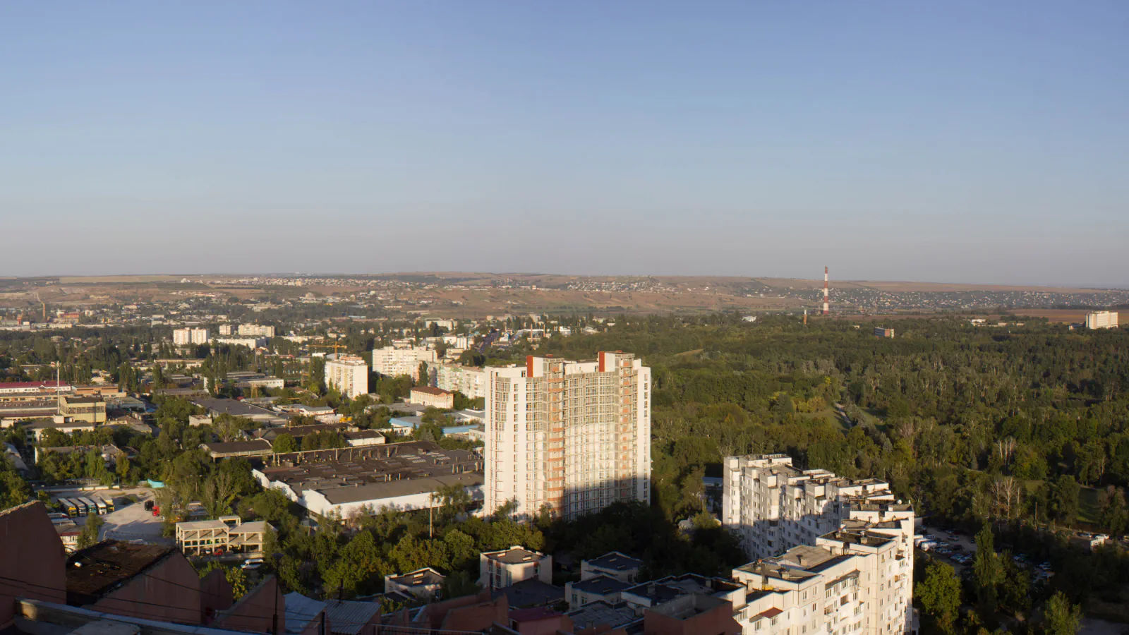 Strehe, stanovanjski bloki in gozdnati griči, vidni s stavbe Porțile Orașului v Kišinjevu