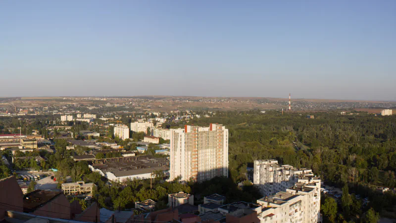 Rooftops, apartment blocks and wooded hills seen from the Porțile Orașului building in Chișinău