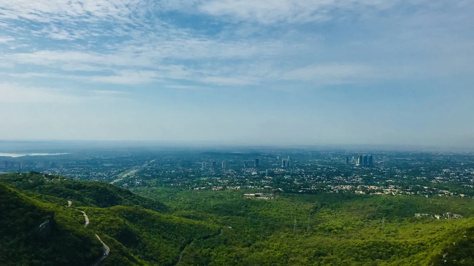 Zeleni griči v ospredju in mesto Islamabad v daljavi