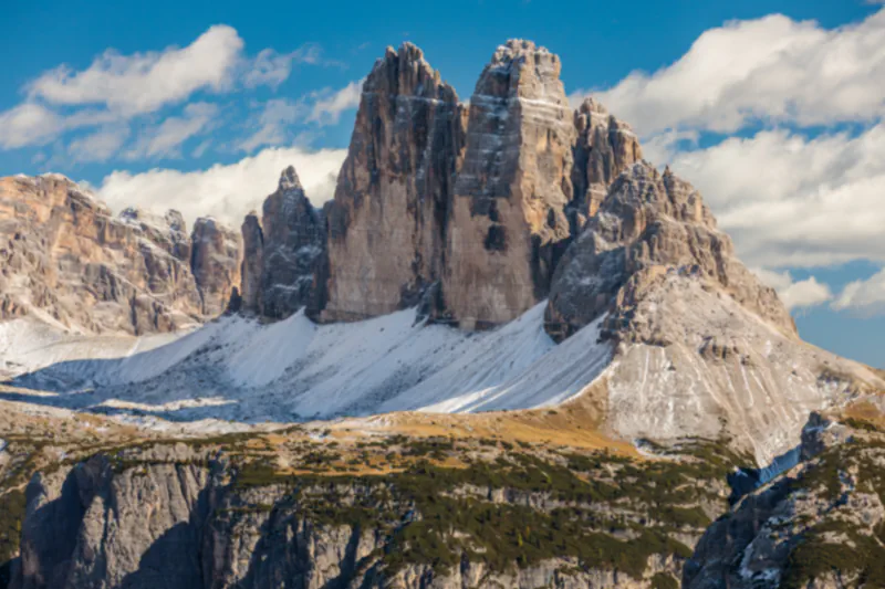 Tre Cime di Lavaredo with snow on their rocky slopes, seen from Monte Specie in the Italian Dolomites