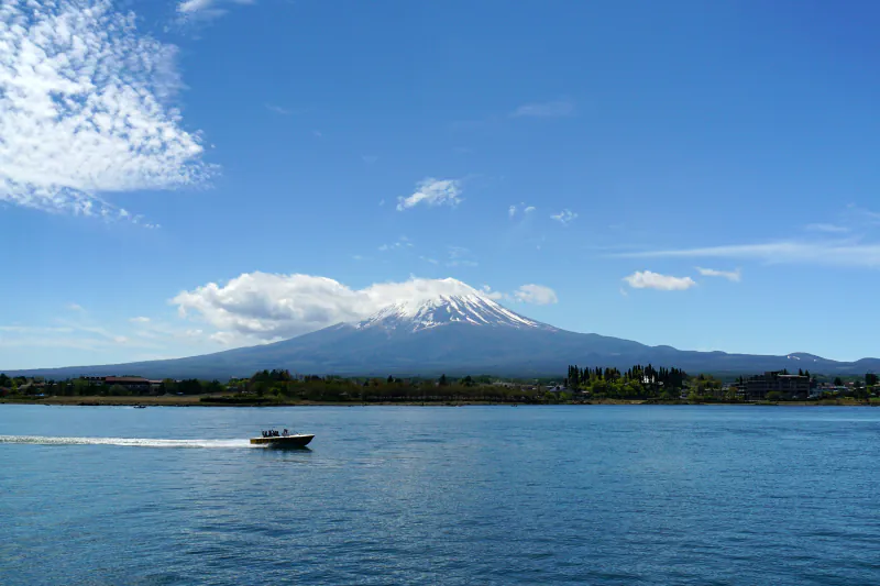 Mount Fuji beyond Lake Kawaguchiko, with a small boat on the water