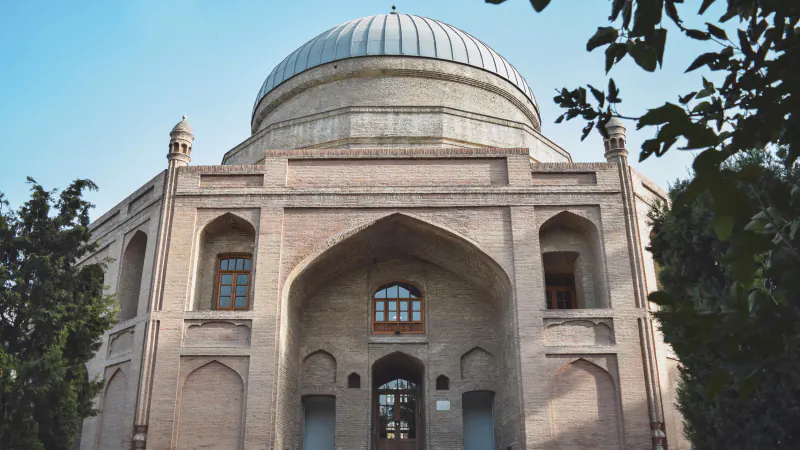 The brick Timur Shah Mausoleum in Kabul, with a ribbed outer dome on a high drum above a large pointed iwan and two small corner turrets