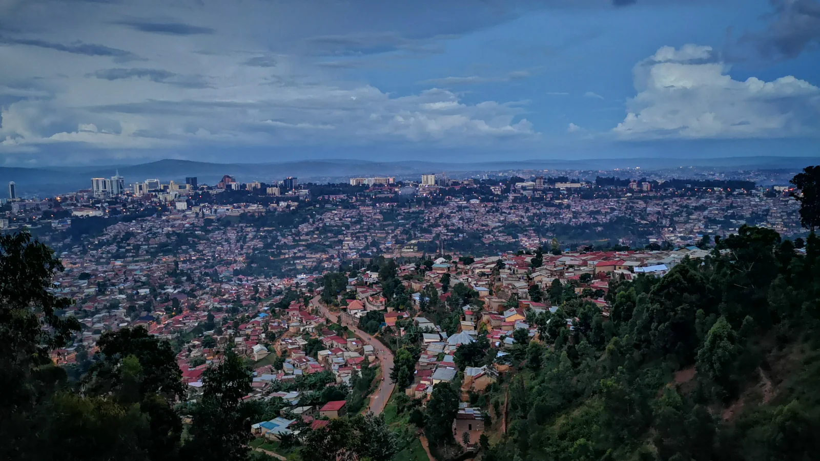 Soseske Kigalija na zelenih pobočjih pod oblačnim nebom