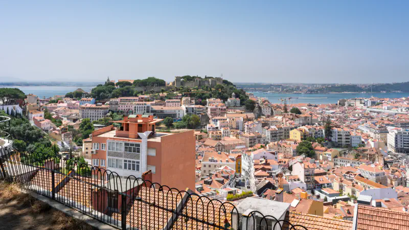 Lisbon rooftops, a hilltop castle and the Tagus seen from a high viewpoint