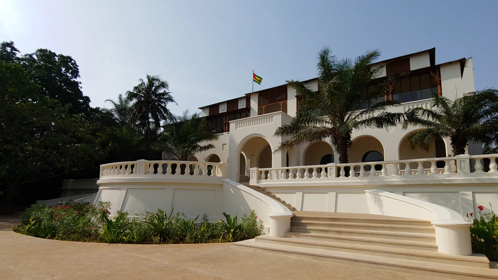 White Palais de Lomé façade with steps, arcades and palms