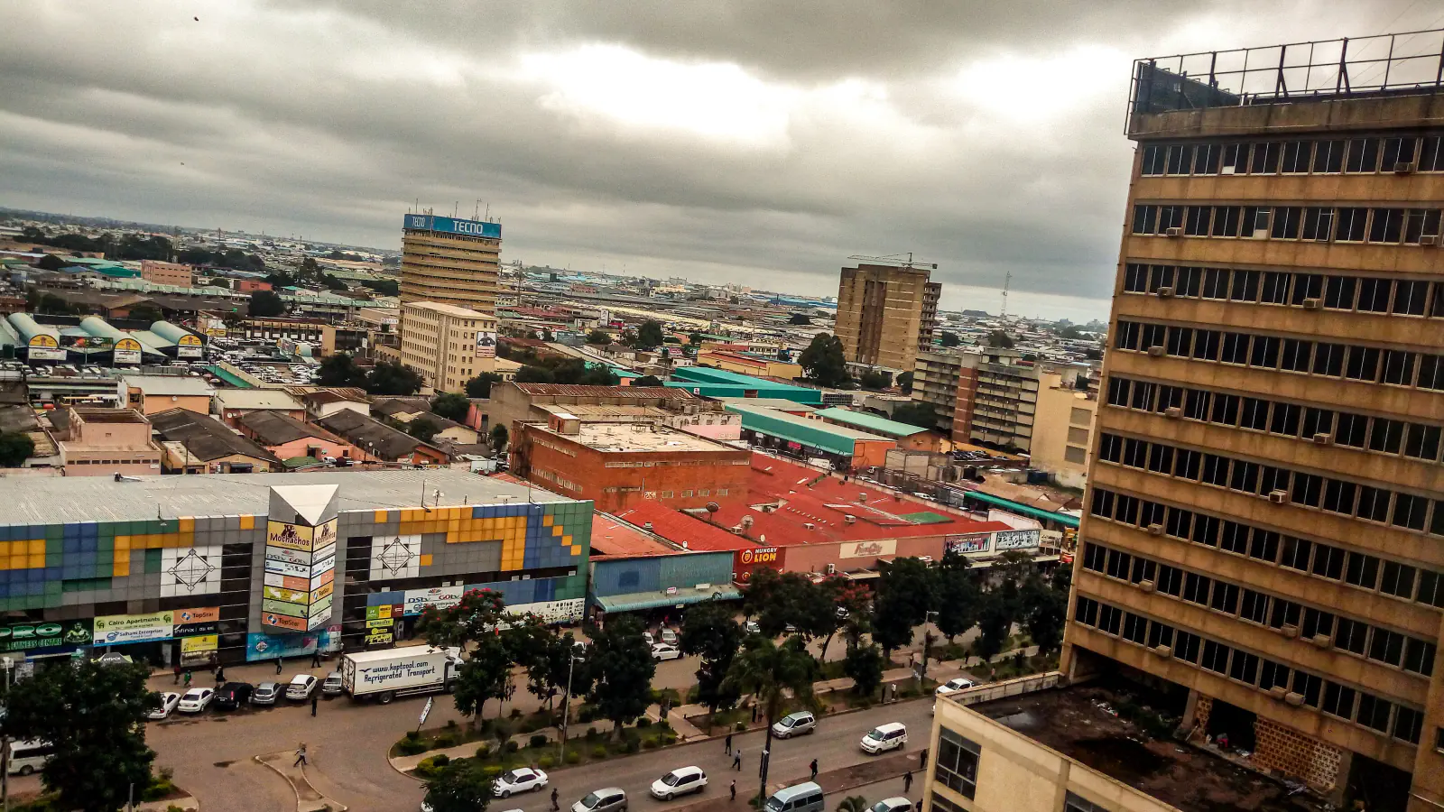 Elevated view over Lusaka’s streets and low and mid-rise buildings under a cloudy sky.