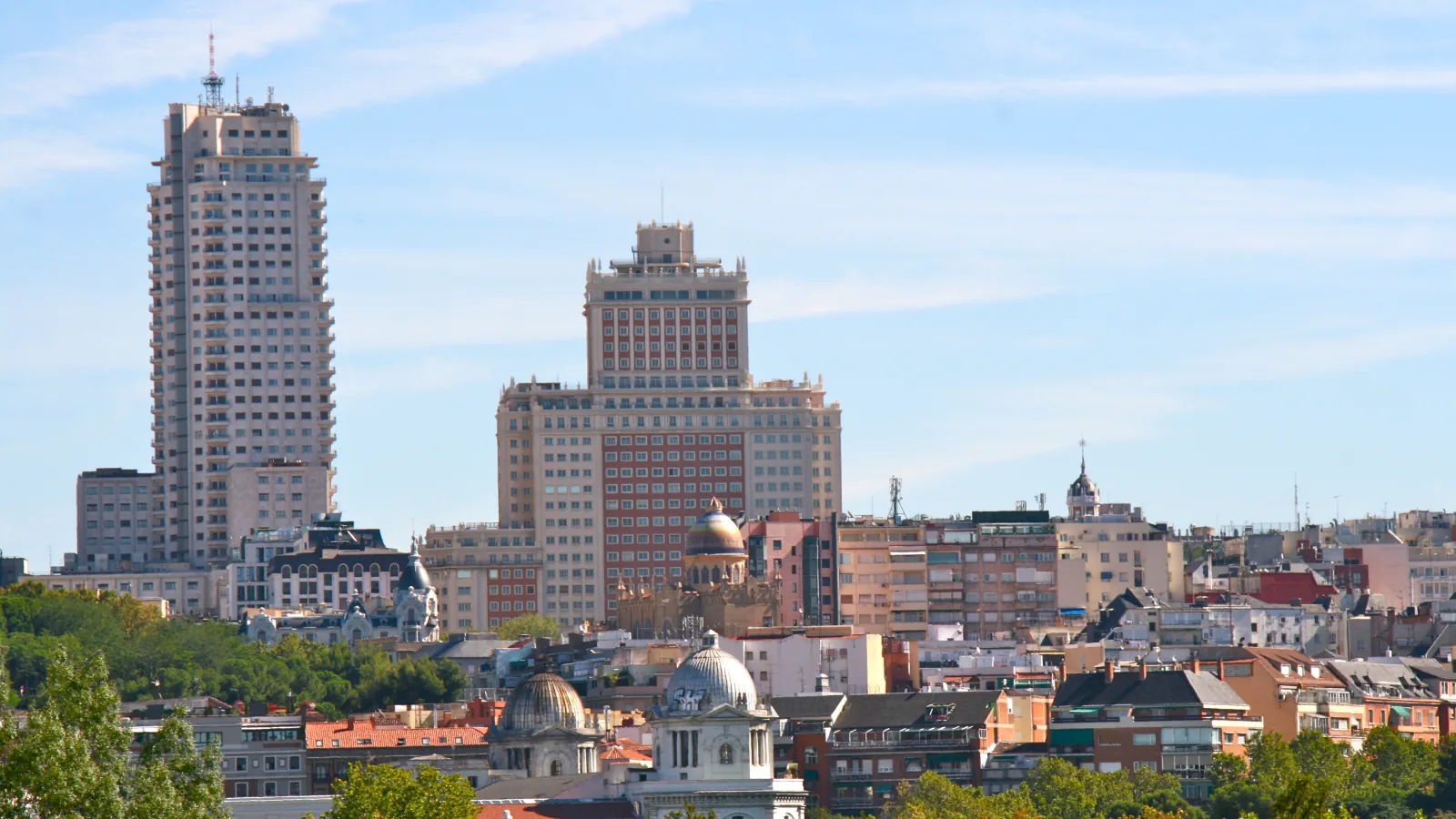 Madrid skyline with Plaza de España towers, domed roofs and a foreground of trees