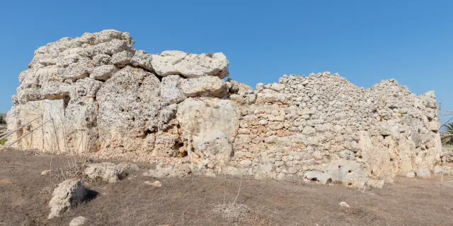 Weathered limestone wall of the Ġgantija temples, with large blocks on the left and smaller stones on the right, under a clear sky