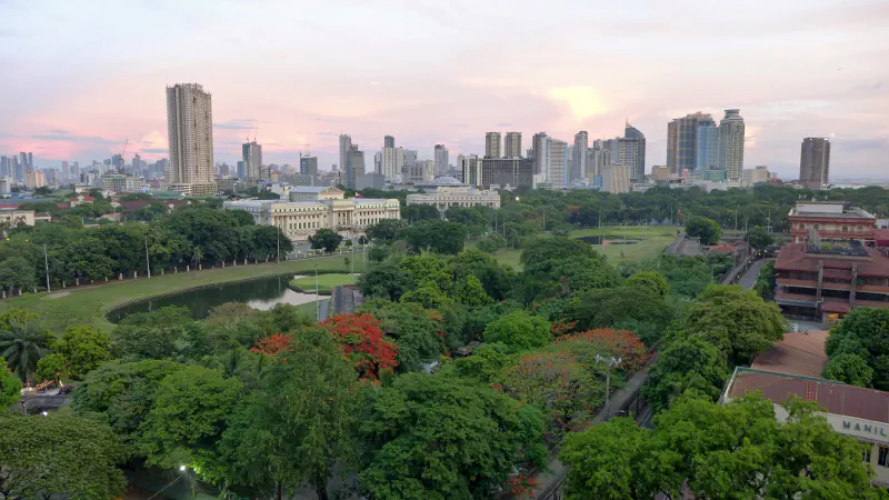 Trees, a pond and neoclassical buildings with Manila’s skyline beyond