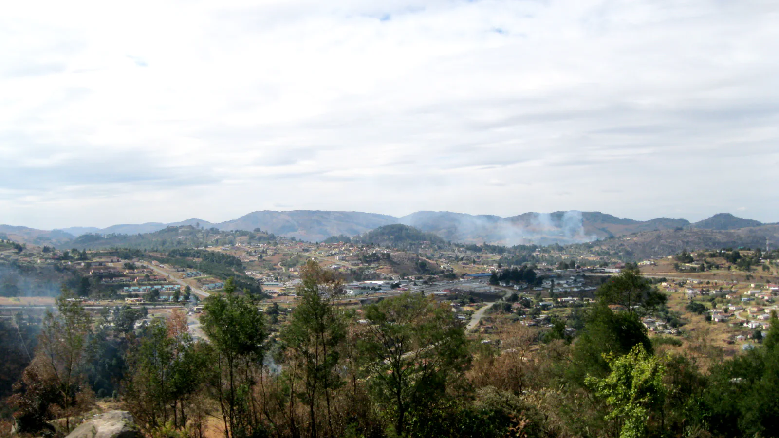 Built areas of Mbabane spread across hills beneath a bright sky