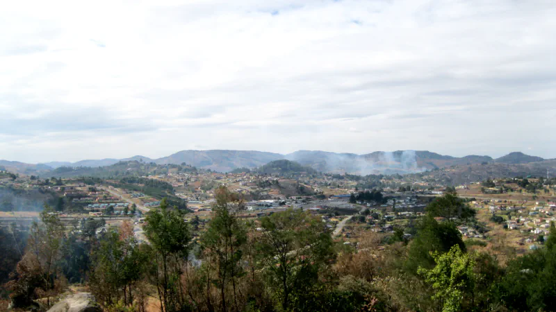 Built areas of Mbabane spread across hills beneath a bright sky
