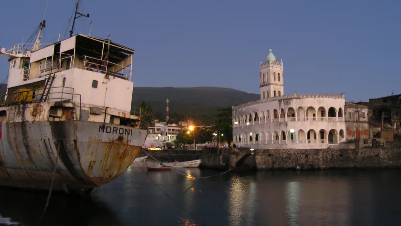 The Old Friday Mosque at Moroni’s old harbour, with a moored ship and smaller boats.