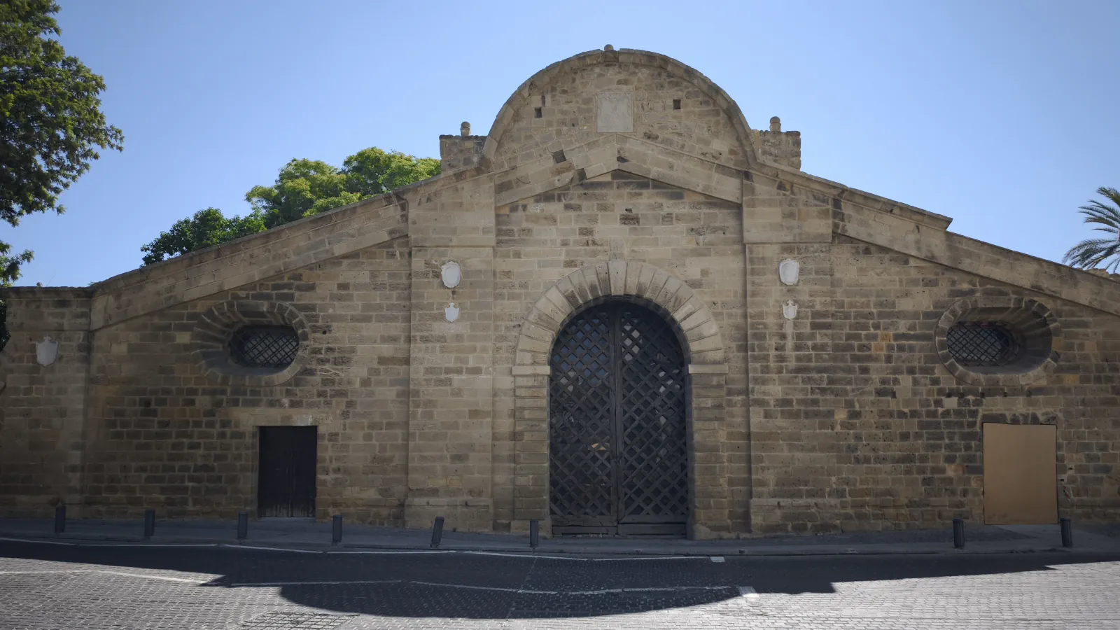Famagusta Gate in Nicosia: a long stone gatehouse with a rounded gable, a tall arched wooden lattice door and an oval window on each side, seen from the street