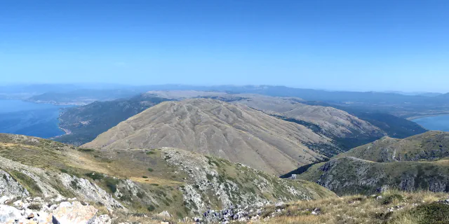 Lake Ohrid and Lake Prespa seen from the upper slopes of Galičica, with a bare mountain slope in front under a clear blue sky