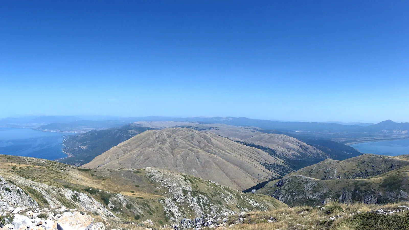 Ohridsko in Prespansko jezero, gledani z višjih pobočij Galičice, spredaj golo gorsko pobočje pod jasnim modrim nebom