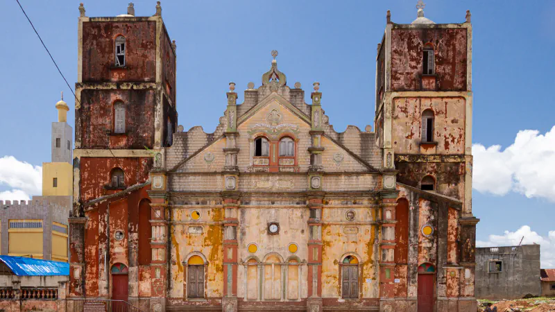 Dva stolpa in okrašen zatrep na večbarvnem pročelju mošeje Grande Mosquée v Porto-Novu pod modrim nebom.