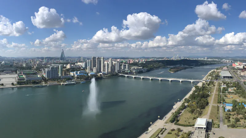 Mestna panorama Pjongjanga, reka in mostovi pod svetlimi oblaki