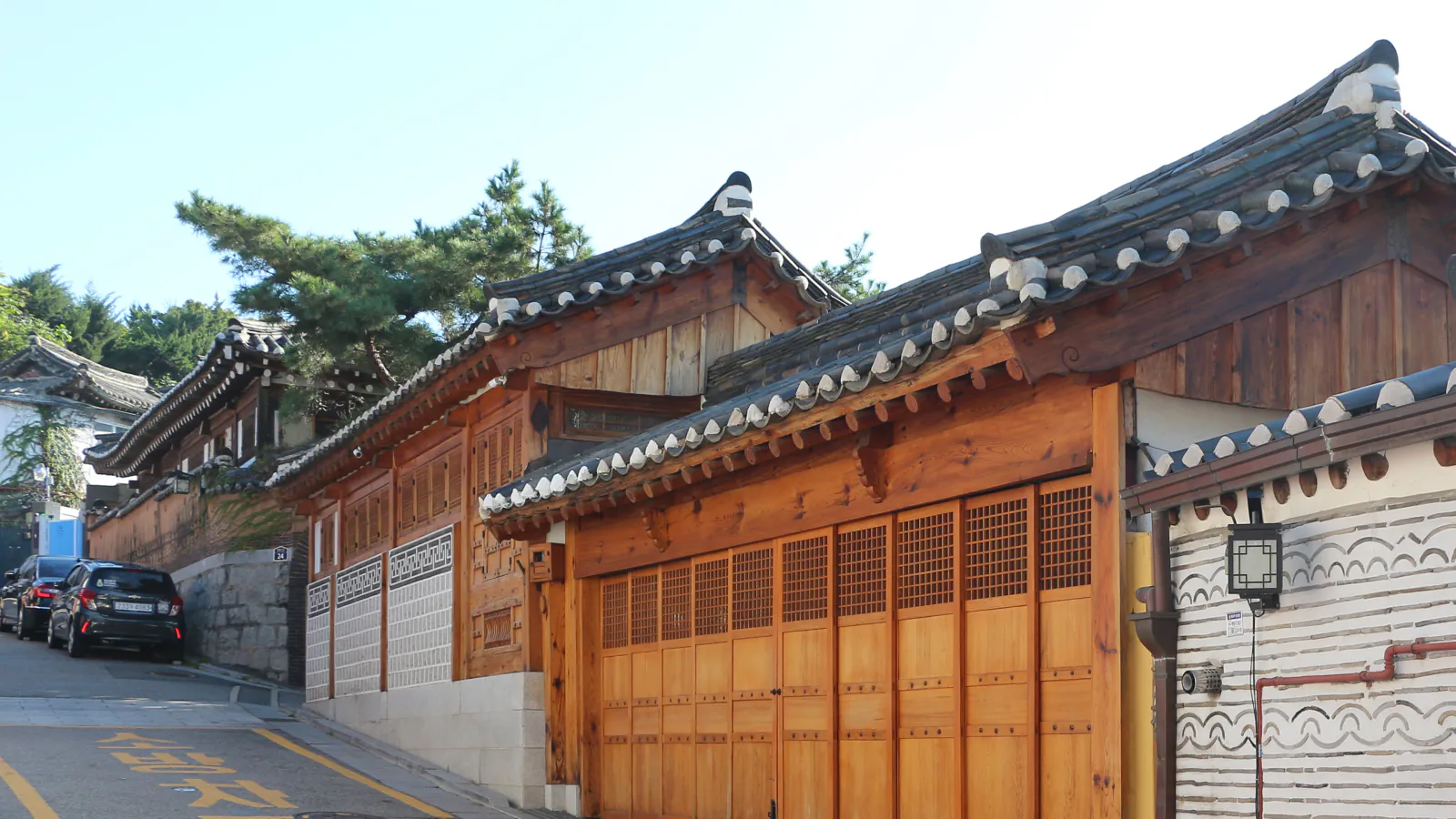 Tradicionalne hiše hanok s strešniki in lesenimi stenami ob ozki ulici v Seulu