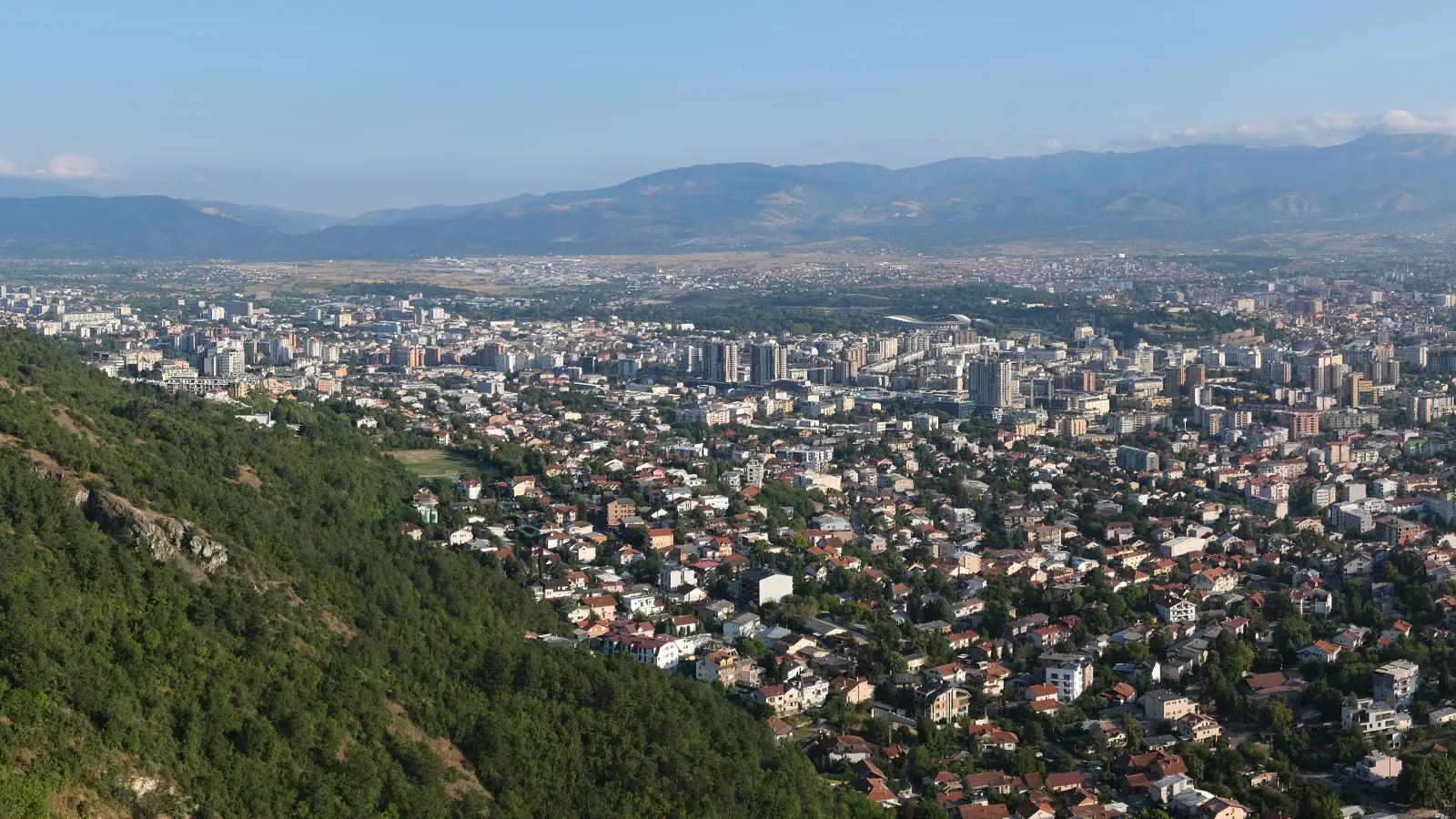Skopje rooftops and city districts with wooded slopes in the foreground