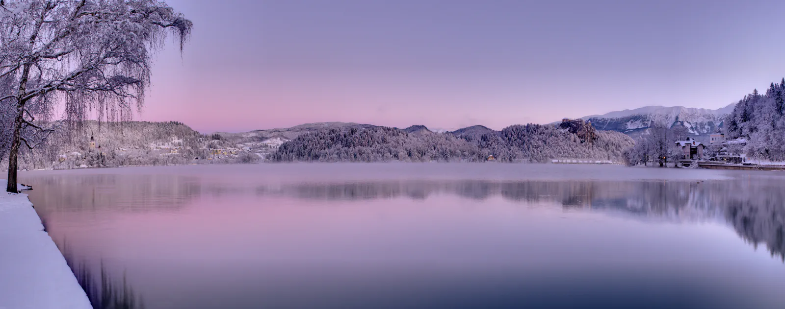 Snow-covered shores and hills reflected in Lake Bled, Slovenia
