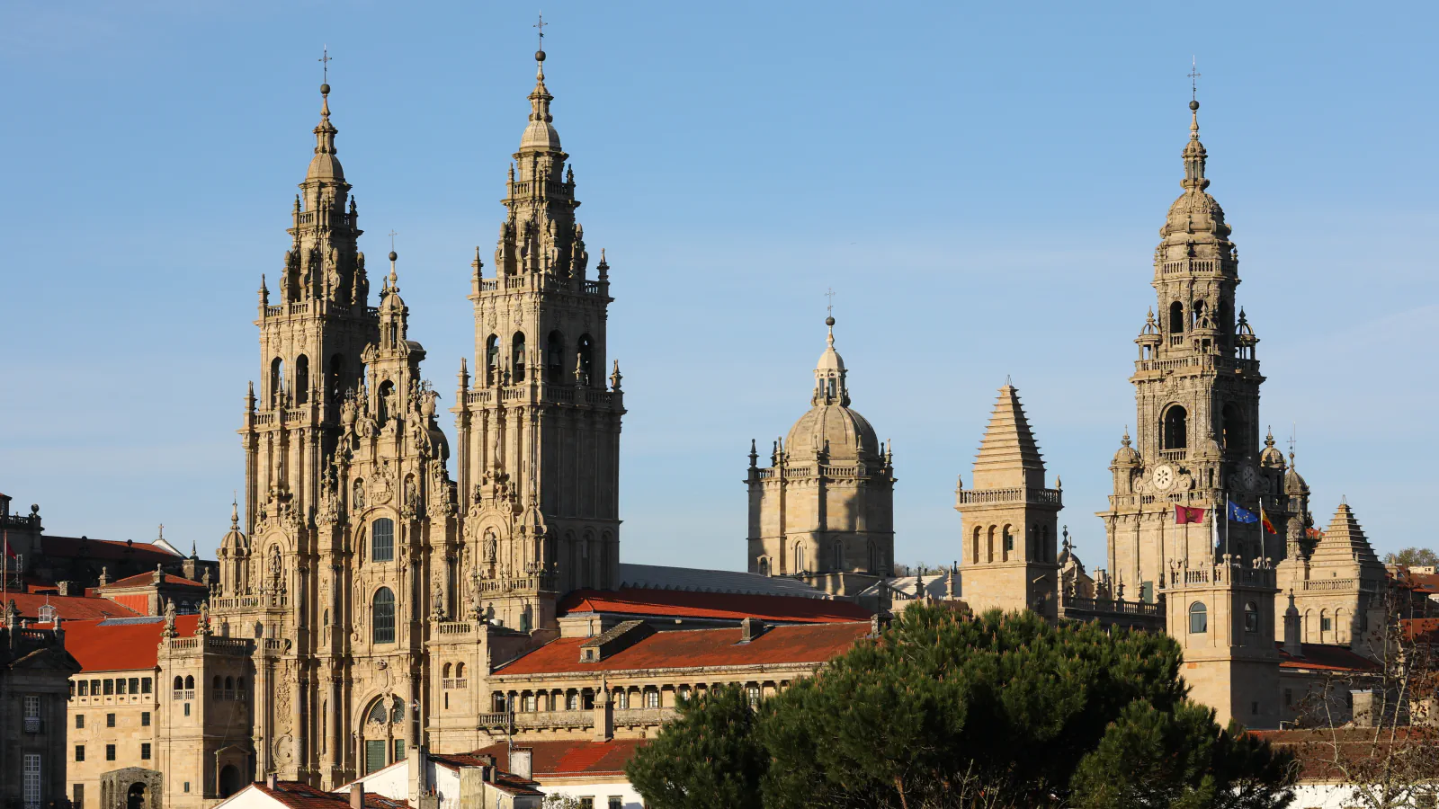 Twin towers of Santiago de Compostela Cathedral’s Obradoiro façade above red-tiled roofs, with the cathedral’s other towers to the right