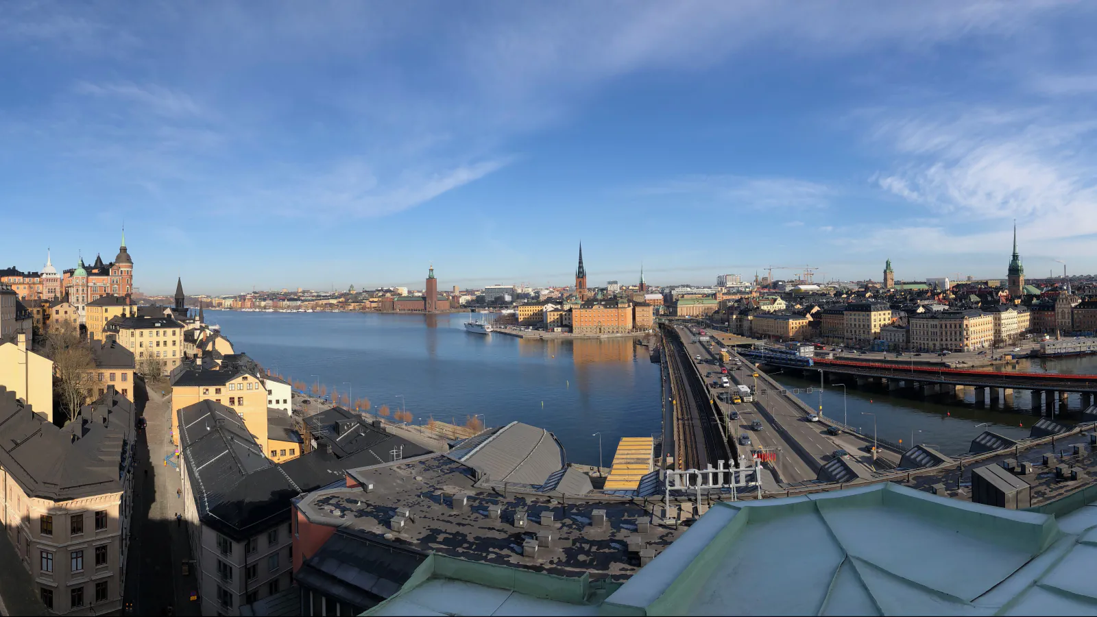 A wide view across the water in Stockholm, with the City Hall tower in the distance, church spires and rooftops.