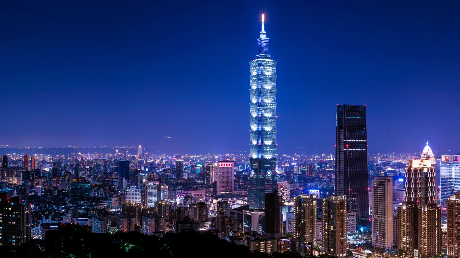 Taipei’s illuminated night skyline, with Taipei 101 rising above the surrounding towers.