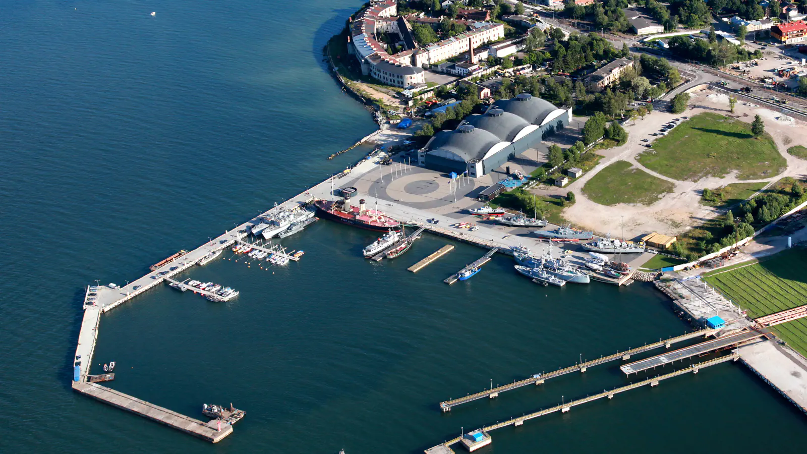 Pogled iz zraka na hangarje Lennusadam in pomol z muzejsko ladjo ter drugimi plovili ob obali