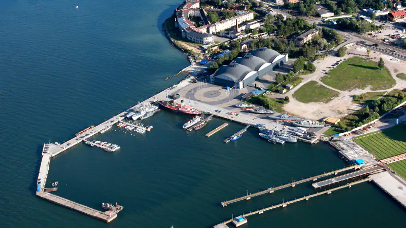 Pogled iz zraka na hangarje Lennusadam in pomol z muzejsko ladjo ter drugimi plovili ob obali