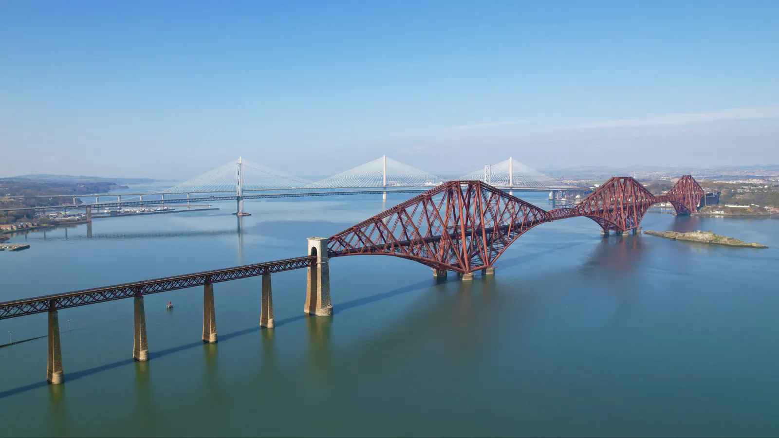 Rdeči železniški most prečka Firth of Forth; v ozadju sta vidna cestna mostova.