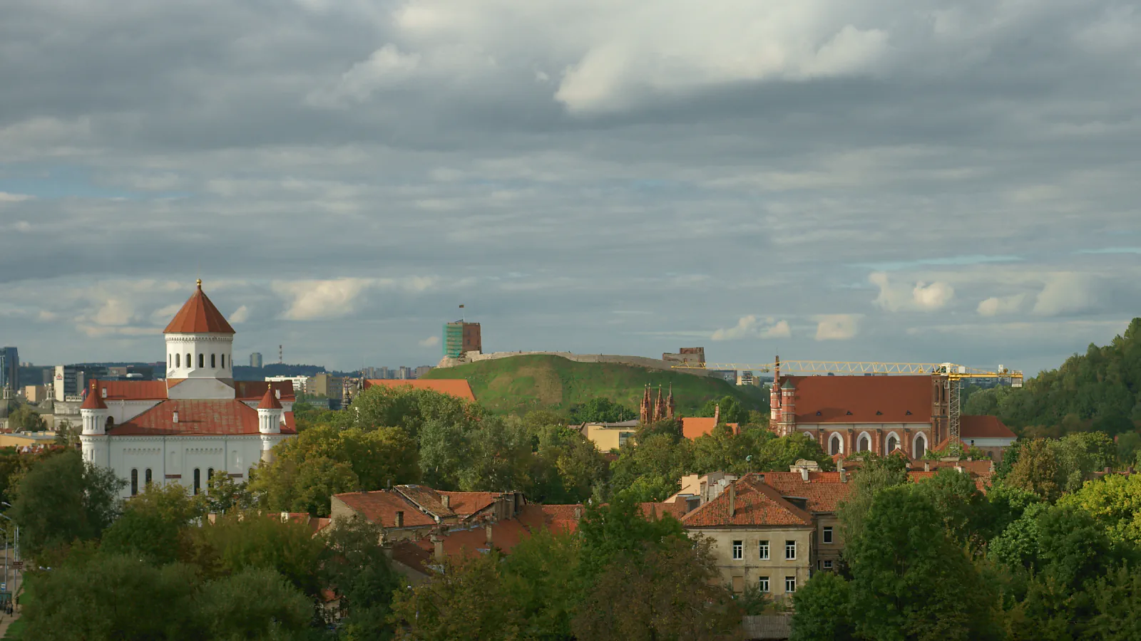 Vilnius roofs, a red-roofed church and a hill beneath a cloudy sky